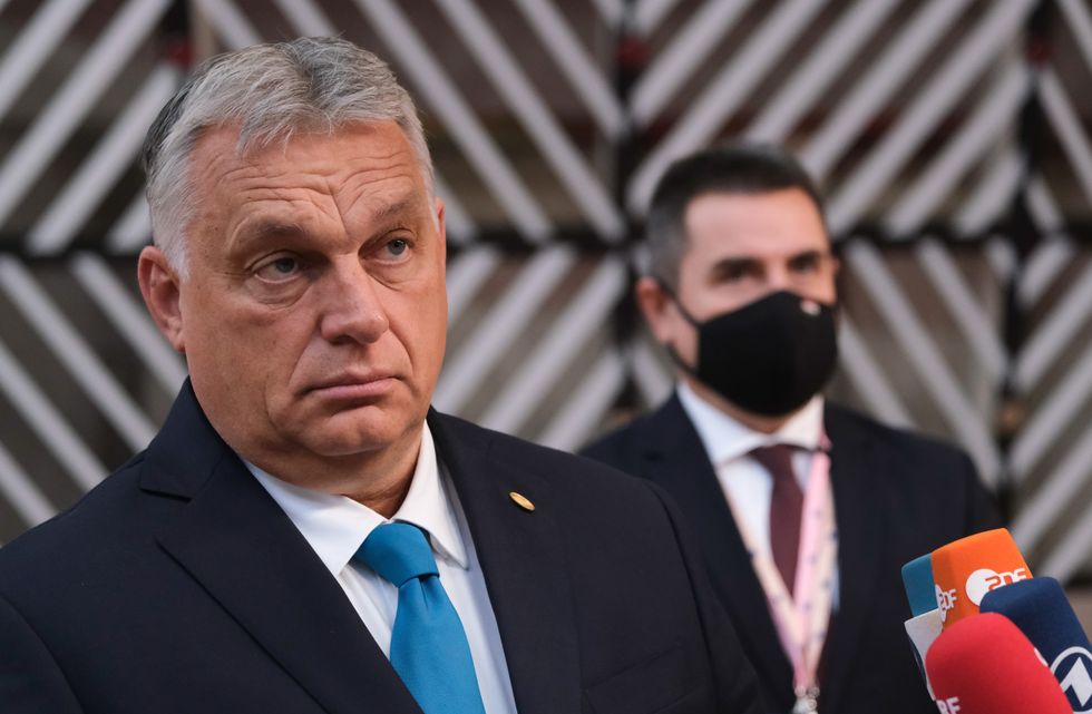 An older man wearing a suit looks at the camera