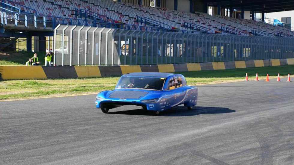 An unusually shaped bright blue car on the racetrack