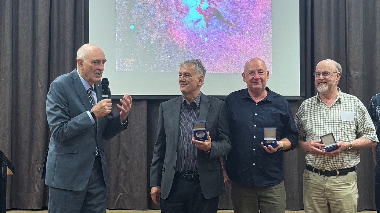 Four middle aged men getting a medal