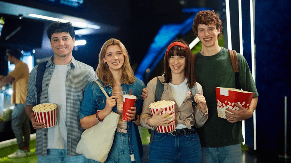 Four young people visiting the cinema with their popcorn