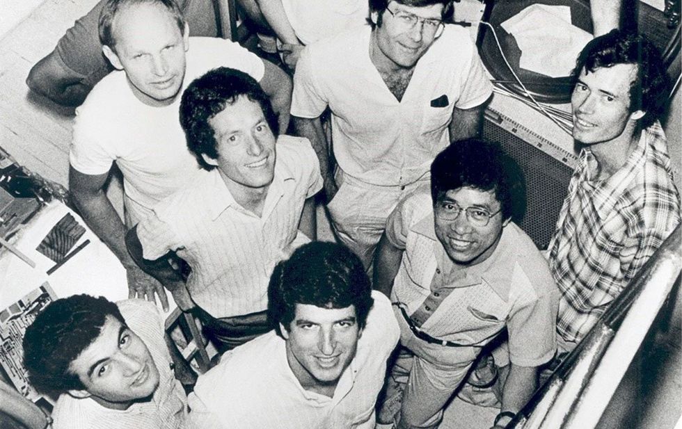 Historical photo of a group of seven young men, shot from above, looking up.