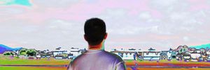 Back view of a young Chinese man looking at a row of houses in the distance.