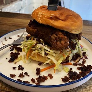 Image of wall sign at Soul Burger restaurant saying plant-based burgers, inset with a picture of a plant-based chicken burger.