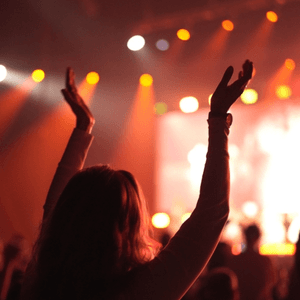 A man in a suit, a girl in the audience at a concert, the Woolworths banner