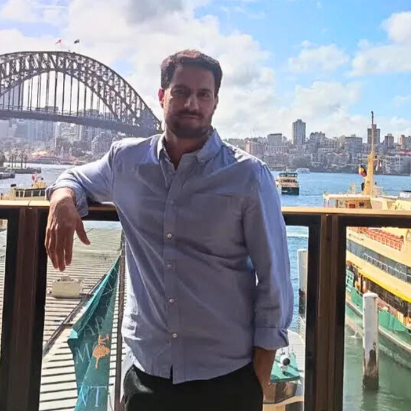 Man at Circular Quay standing with his back to the Sydney Harbour Bridge and the ferries