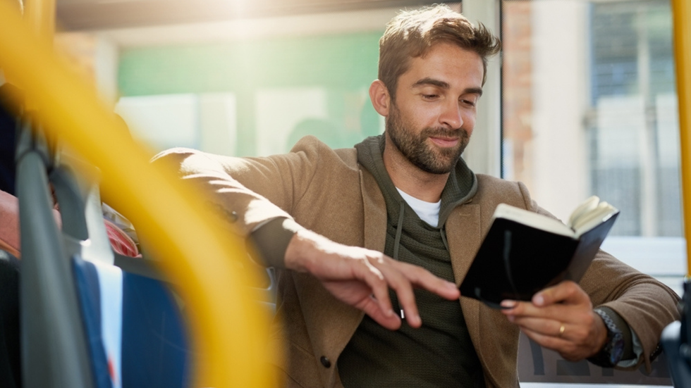 Man on a bus reading a book