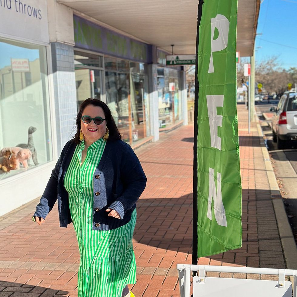 Middle-aged woman walking in sunshine on a shopping street in a country town.