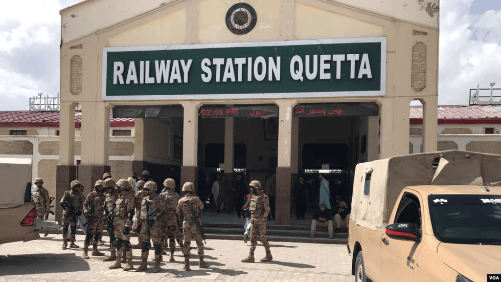 Soldiers in fatigues outside a building with the sign Railway Station Quetta
