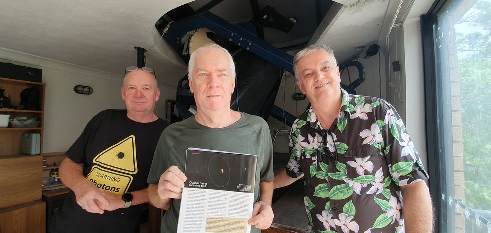 Three middle-aged men holding a magazine article