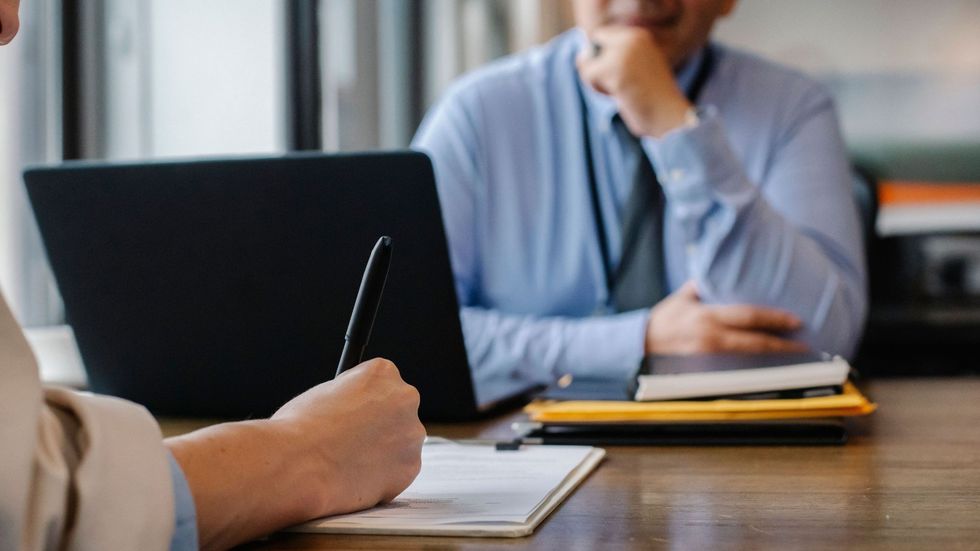 Two men look at each other in a workplace interview setting