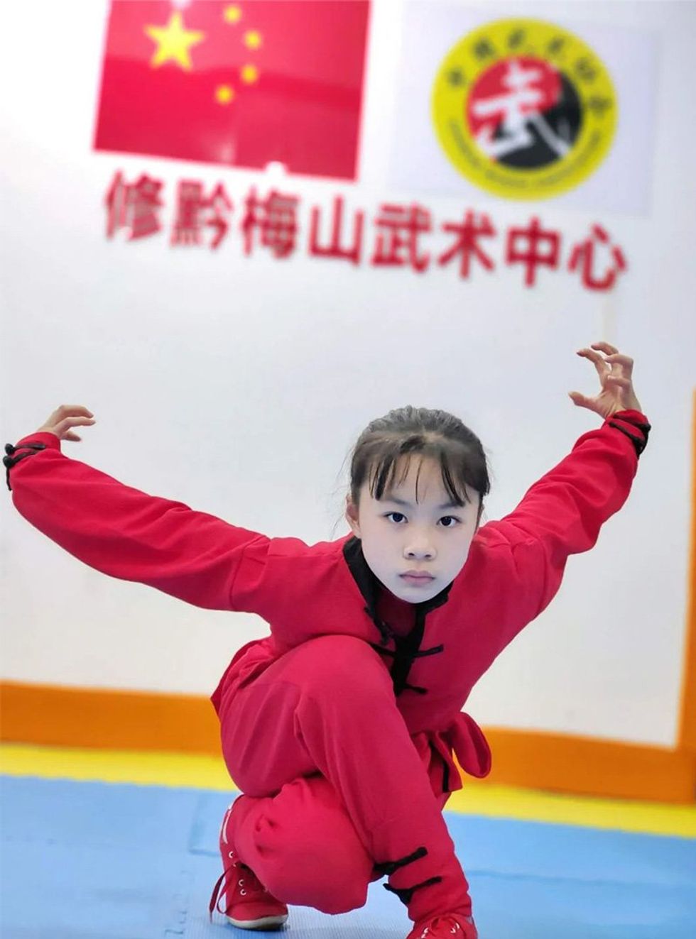 Young girl strikes a wushu competition pose. 