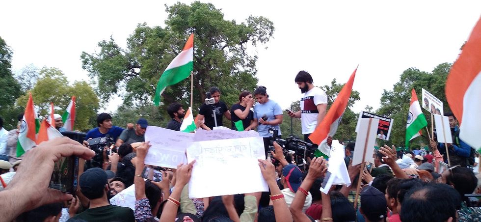 Young people cluster around a speaker surrounded by Indian flags
